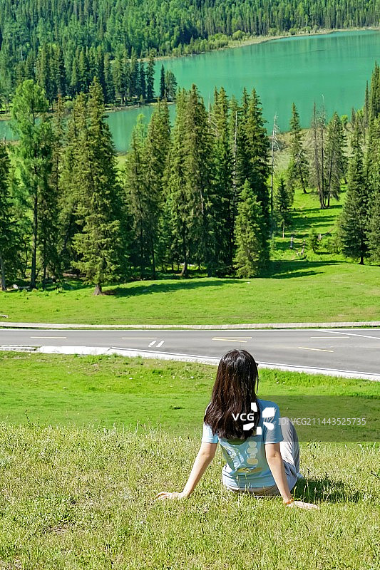 坐在草地上的年轻女子的后视图图片素材