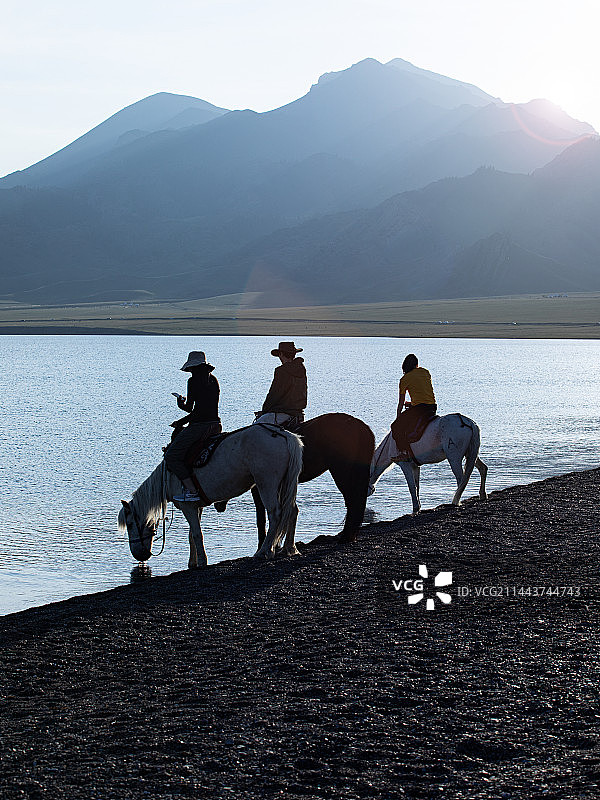 赛里木湖湖边，一群人骑着马，马儿正在湖边喝水图片素材