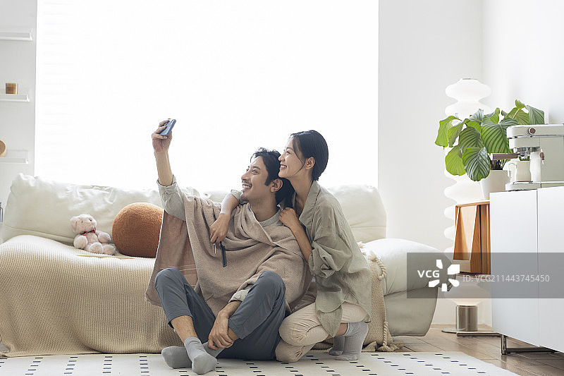 年轻夫妇在客厅理发后，用手机自拍图片素材