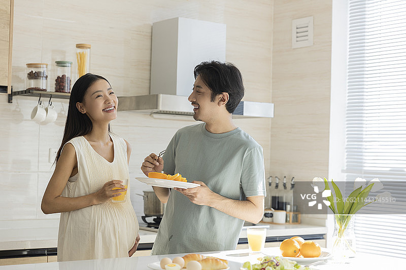 丈夫和怀孕妻子在开敞厨房吃早餐聊天图片素材