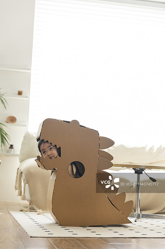 小女孩在客厅玩恐龙纸箱图片素材