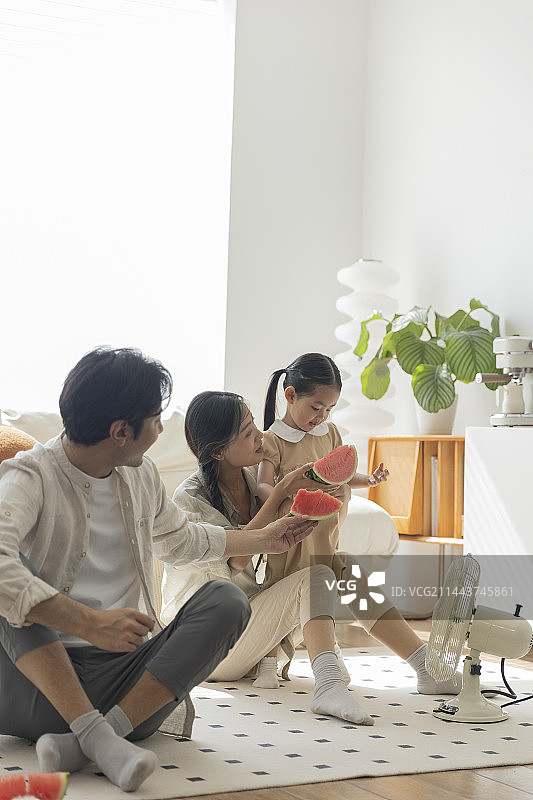 幸福一家人在客厅吃西瓜、吹电风扇图片素材