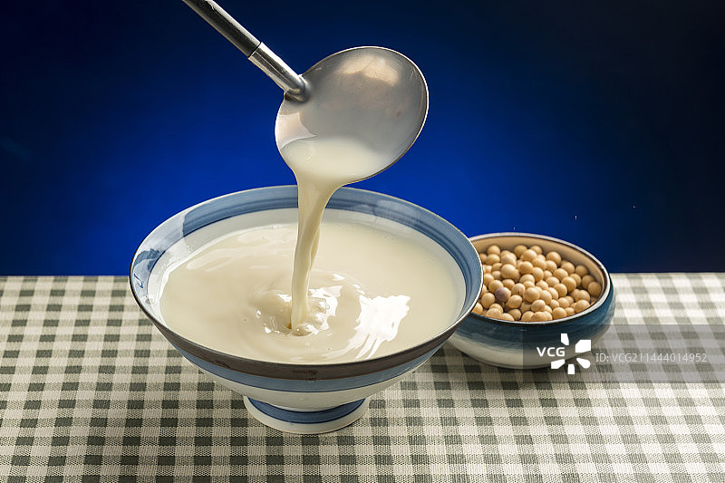 用勺子盛豆浆特写木桌面格子桌布背景图片素材