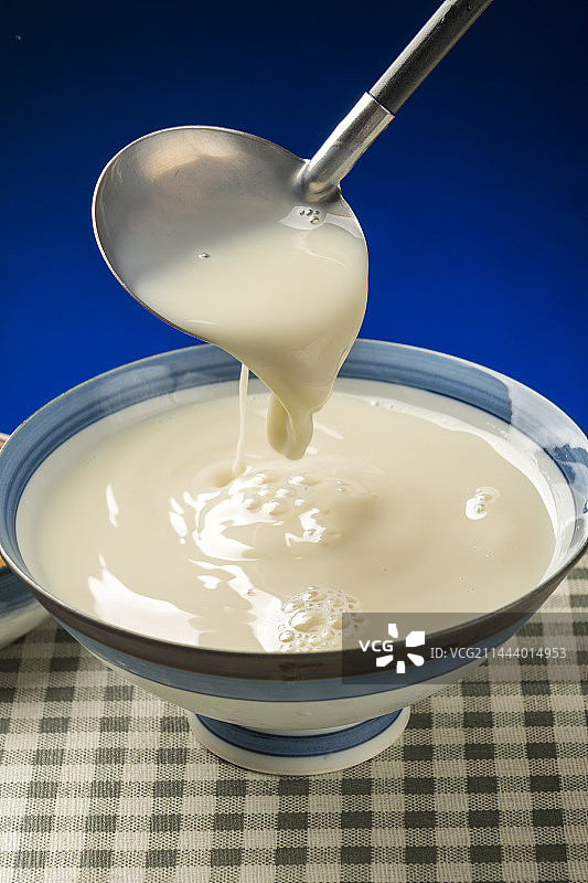 用勺子盛豆浆特写木桌面格子桌布背景图片素材