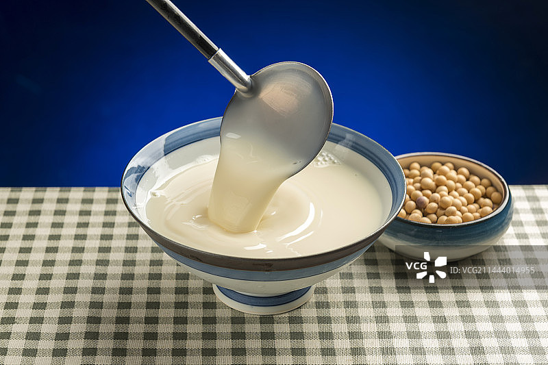 用勺子盛豆浆特写木桌面格子桌布背景图片素材
