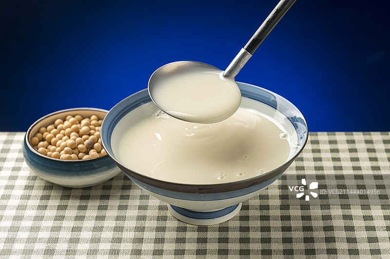 用勺子盛豆浆特写木桌面格子桌布背景图片素材
