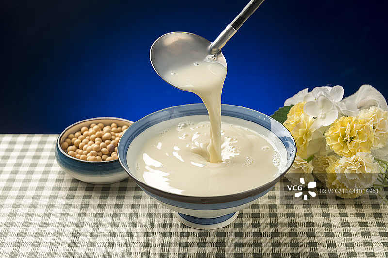 用勺子盛豆浆特写木桌面格子桌布背景图片素材