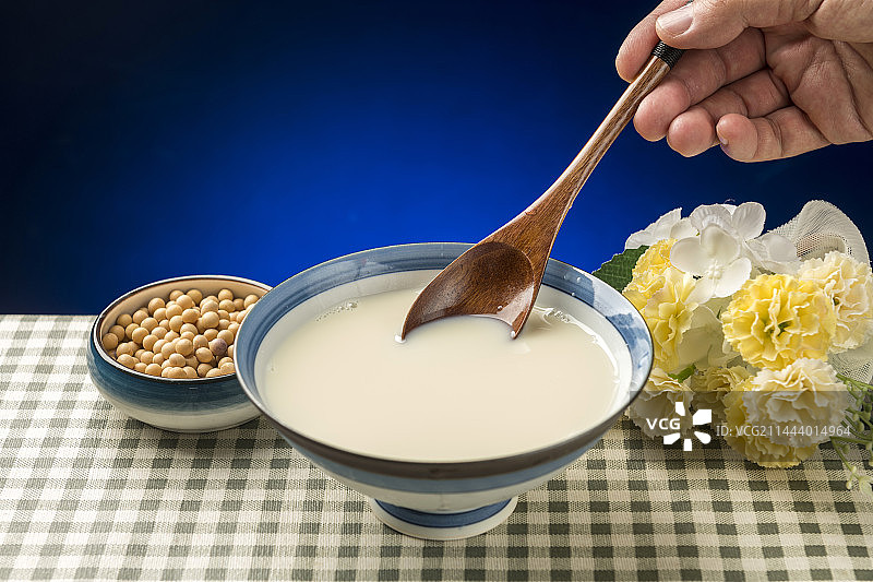 用勺子盛豆浆特写木桌面格子桌布背景图片素材