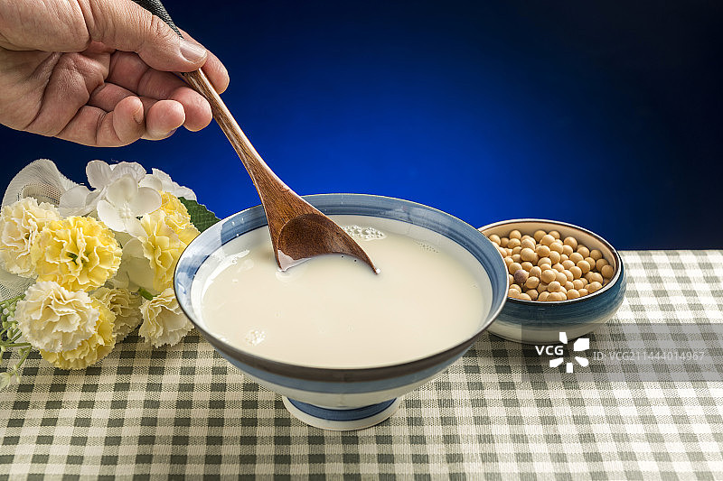 用勺子盛豆浆特写木桌面格子桌布背景图片素材