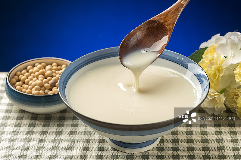 用勺子盛豆浆特写木桌面格子桌布背景图片素材