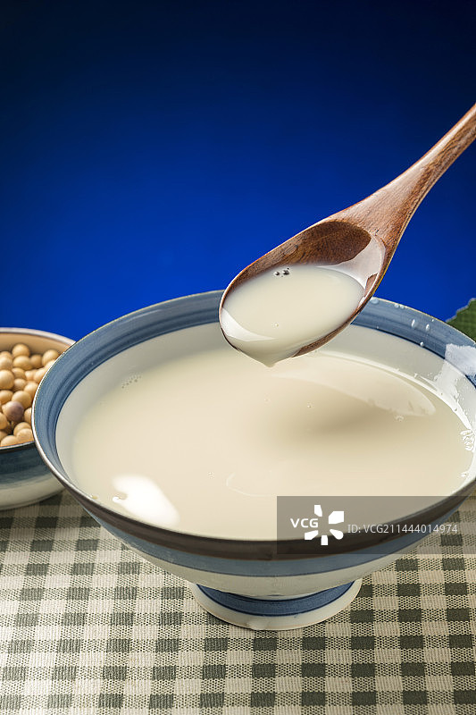 用勺子盛豆浆特写木桌面格子桌布背景图片素材