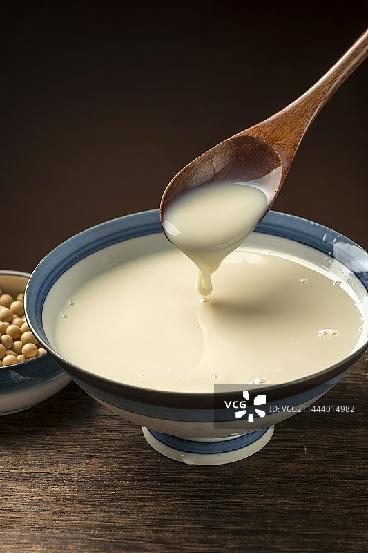 用勺子盛豆浆特写木桌面格子桌布背景图片素材