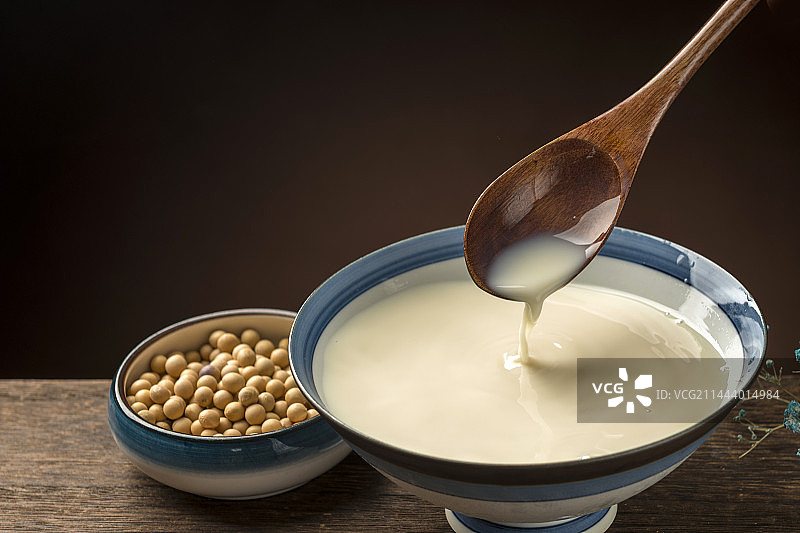 用勺子盛豆浆特写木桌面格子桌布背景图片素材