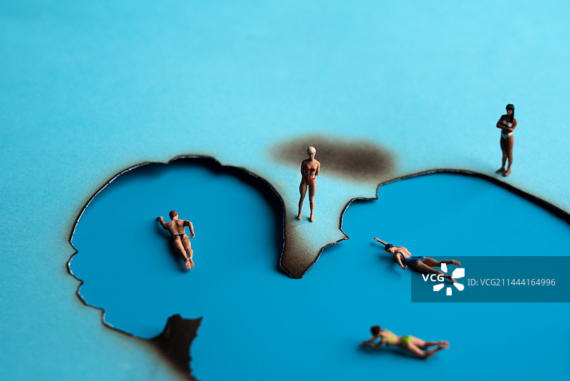 在蓝色纸燃烧后的空洞中游泳的微缩创意图图片素材