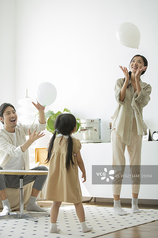 快乐的一家三口在客厅玩气球图片素材