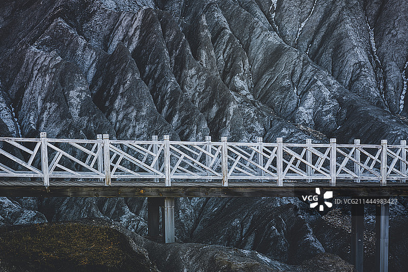 川西甘孜州道孚县八美墨石公园冷色调，黑色石林岩石起伏褶皱，网红白色木桥步道横跨而过图片素材