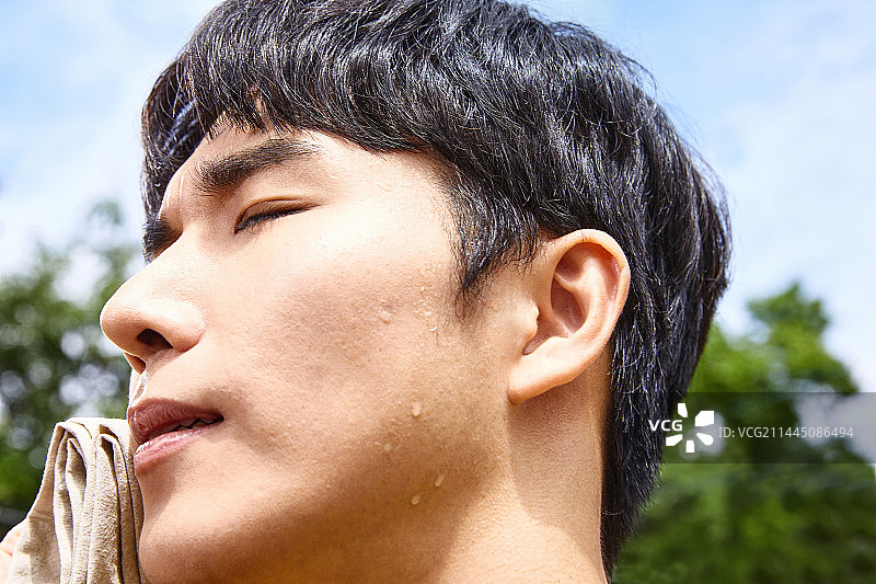 夏季户外擦汗的韩国青年图片素材