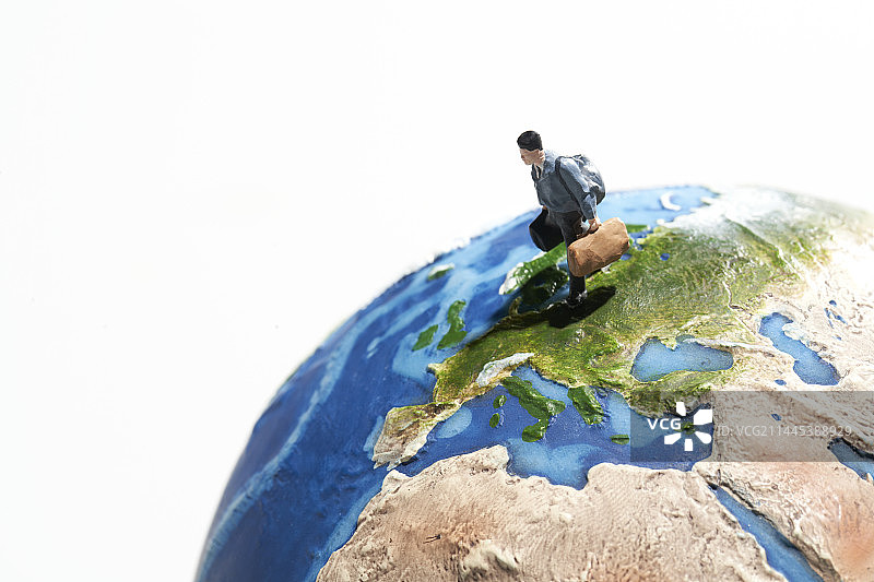 在地球模型上旅行的迷你玩偶图片素材