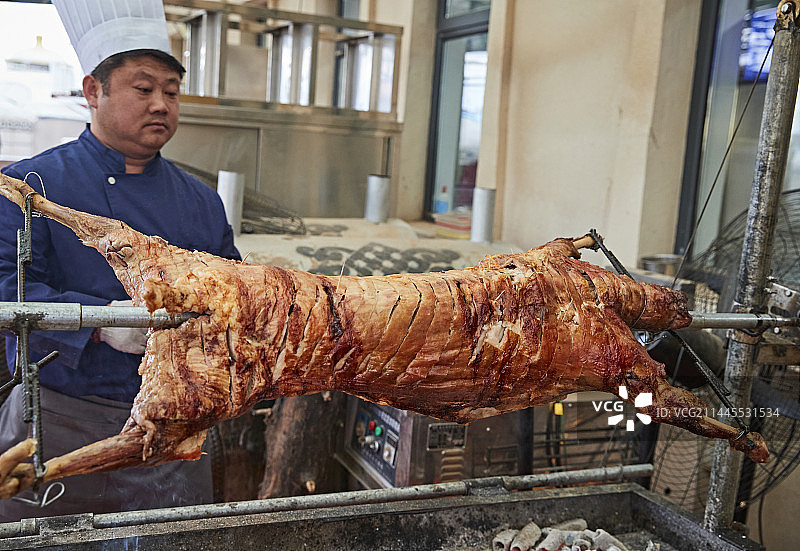 厨师在全神贯注的烤制全羊图片素材