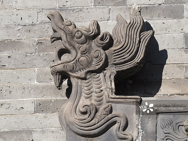 山西榆次古建筑靠墙的龙头雕像特写镜头图片素材