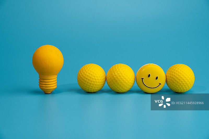 蓝色背景下的黄色笑脸和灯泡微缩创意图图片素材