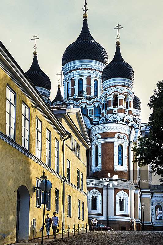 爱沙尼亚塔林：阳光洒满街道，两位游客漫步，背景是亚历山大·涅夫斯基主教座堂图片素材