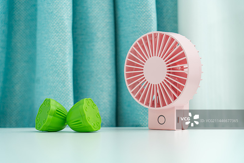 粉色的电扇和莲蓬放在白色桌面上图片素材