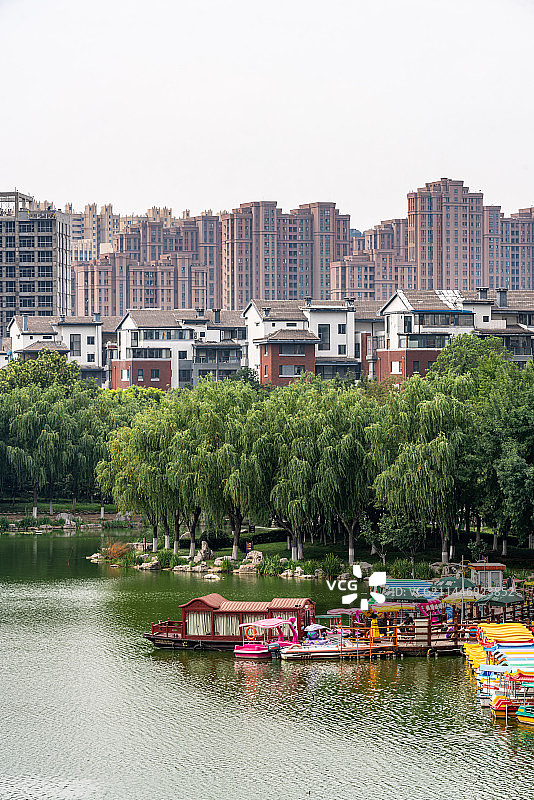 荷花荷叶背景掩映中的山东济宁任城古南池公园建筑济宁城市建筑倒影景观图片素材