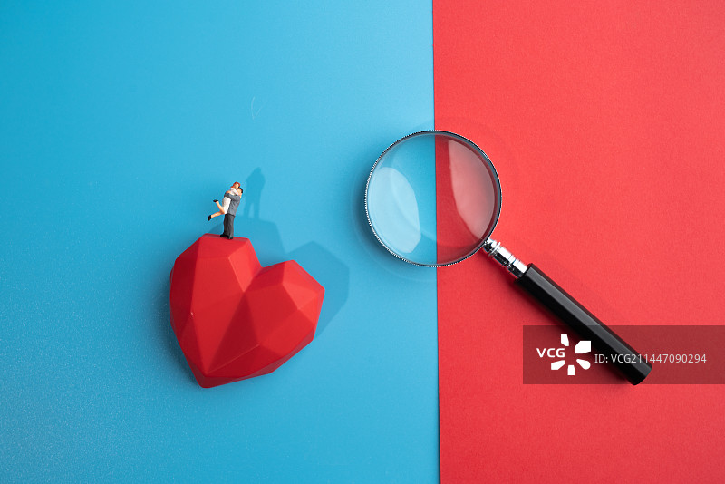 放大镜傍边站在红心爱心上的拥抱的情侣微缩创意图片素材