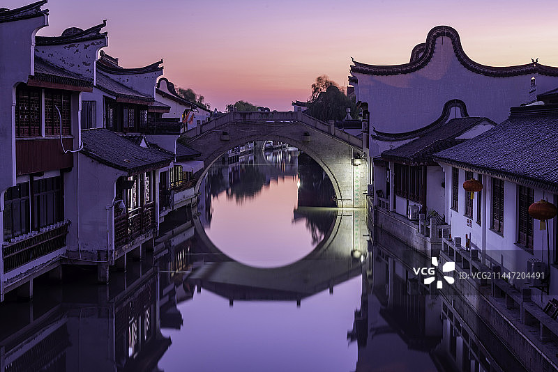 日出时分天边露出粉红色橙黄色的朝霞，闵行召稼楼古镇平静的河面上倒影着古色古香的报恩桥和明清建筑群图片素材