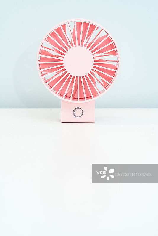 一台手持电风扇放在白色的桌面上图片素材