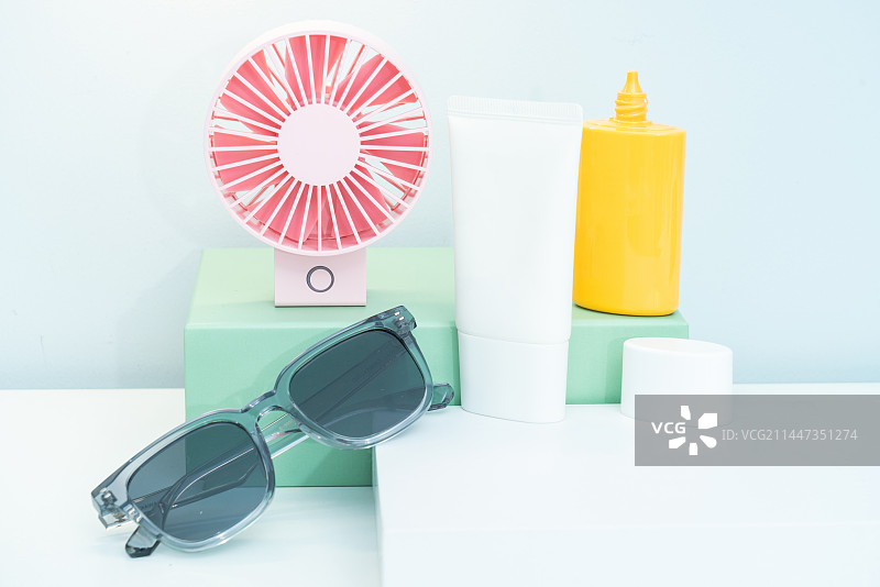 太阳镜和粉色的小电扇放在台面上图片素材