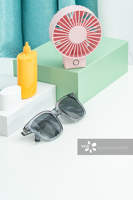 太阳镜和粉色的小电扇放在台面上图片素材