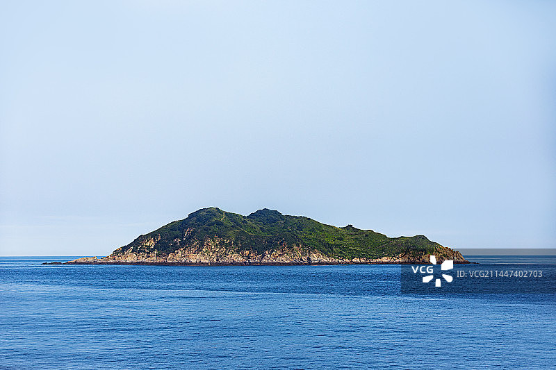 风平浪静的湛蓝色海面上有一个孤零零的小岛图片素材