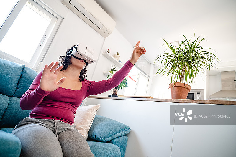 年轻女子在西班牙格拉纳达家中沙发上玩VR图片素材