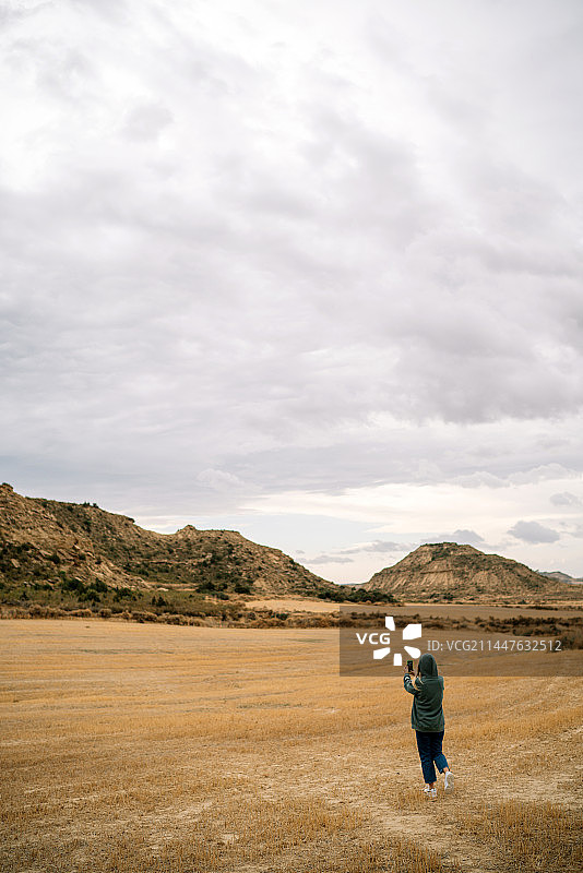 西班牙巴尔德纳斯雷亚莱斯，男孩在多云的天空下走在田野上的背影图片素材