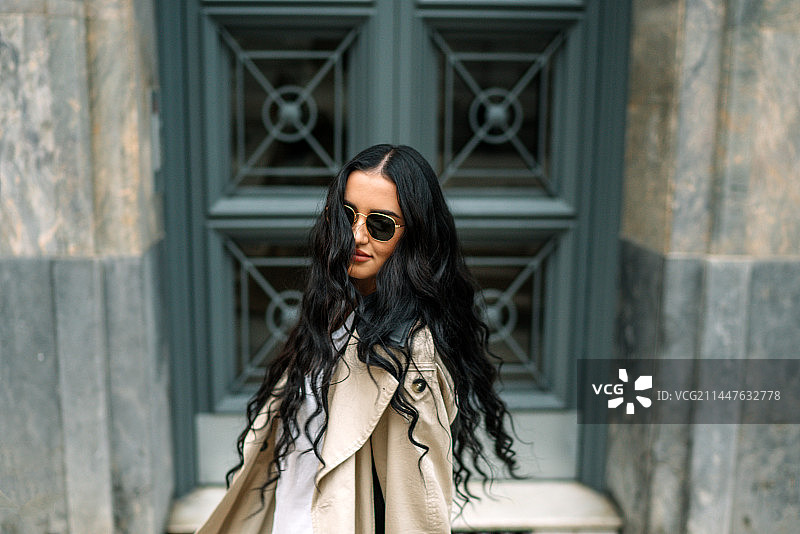 戴着太阳镜站在西班牙建筑物前的年轻女子肖像图片素材