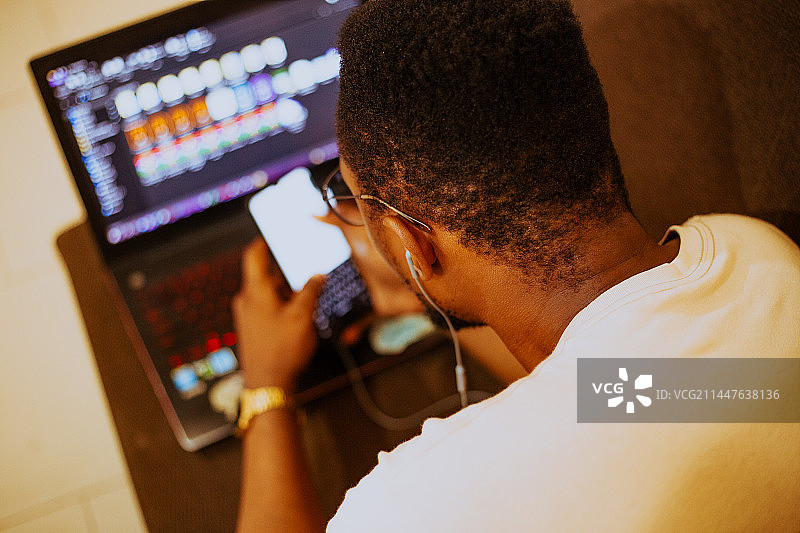 年轻男子使用电脑和手机的后视图，特马，加纳图片素材