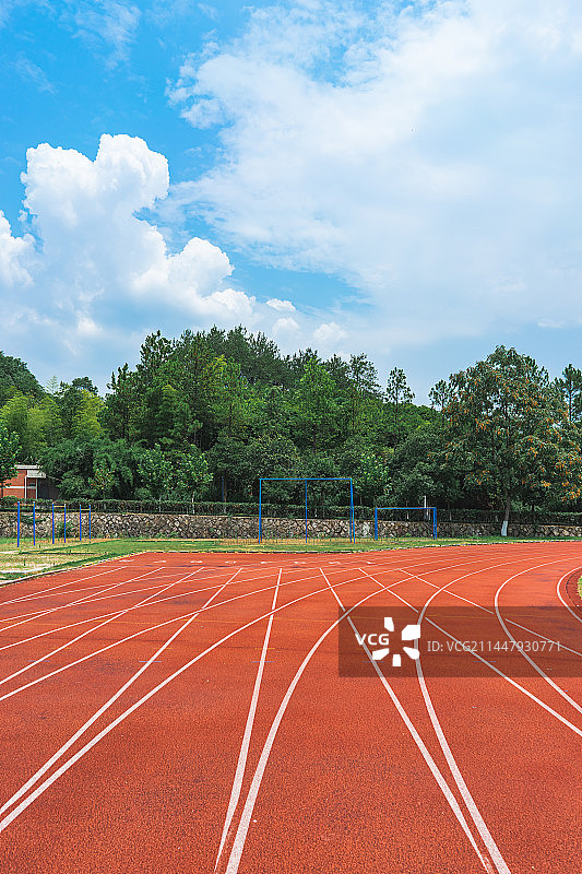 中国学校操场拍摄主题，红色塑胶跑道，天空的云，绿色的操场，看台和建筑外部，户外无人图像摄影图片素材