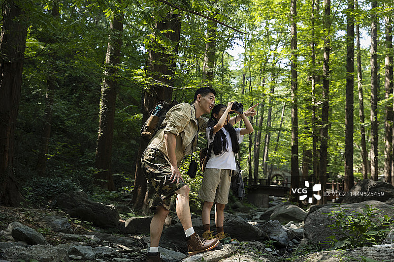 父亲和女儿在杉树森林中用望远镜探索大自然图片素材