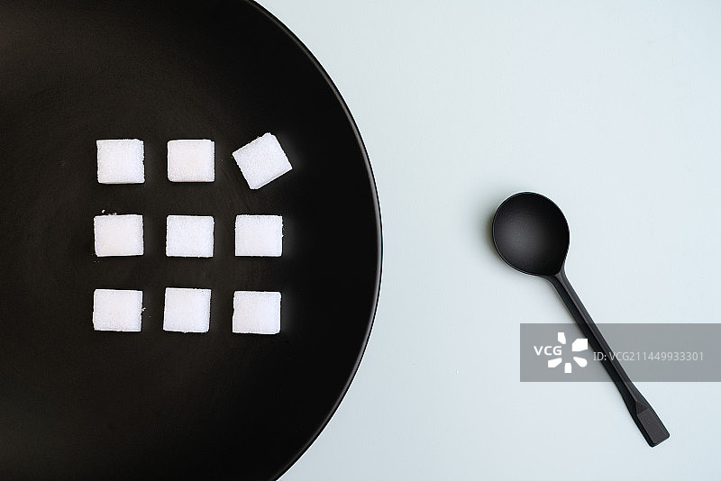黑白背景中的白色方糖和黑色勺子微缩创意图片素材