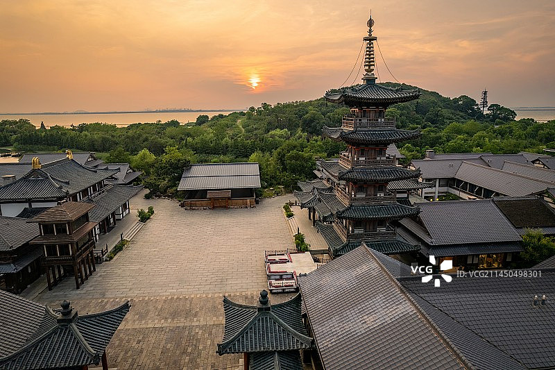 航拍日落时分温暖的阳光照射在滨湖区马山拈花湾拈花湖古色古香的唐风建筑和拈花塔，天边火红温暖的晚霞图片素材