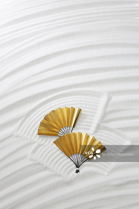 白色沙滩上用金色扇子绘制的曲线图片素材