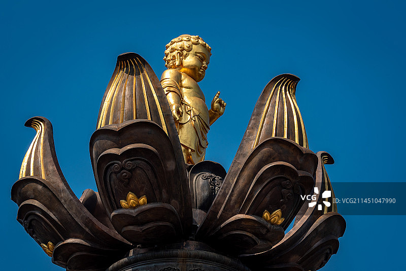 无锡灵山胜境九龙灌浴是国内最大的音乐动态青铜雕塑群，讲述释迦摩尼出生故事，蓝天下金色雕塑白色喷泉水柱图片素材