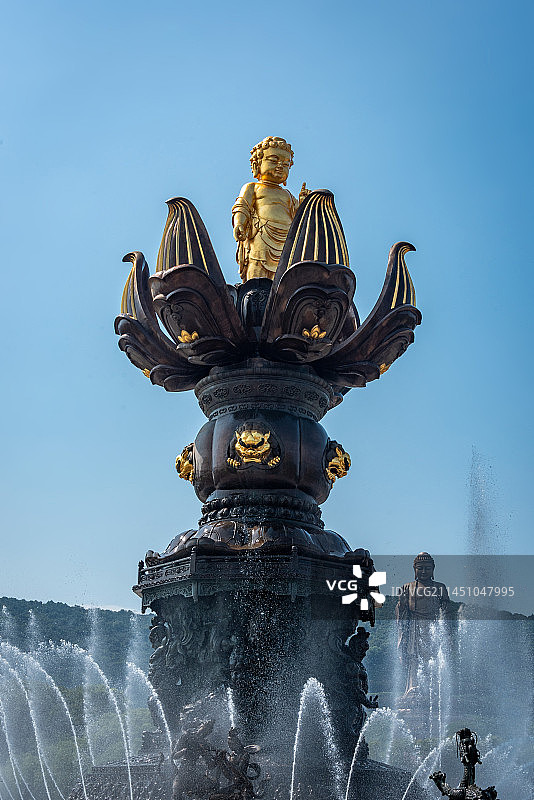无锡灵山胜境九龙灌浴是国内最大的音乐动态青铜雕塑群，讲述释迦摩尼出生故事，蓝天下金色雕塑白色喷泉水柱图片素材
