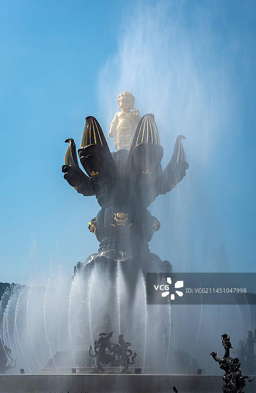 无锡灵山胜境九龙灌浴是国内最大的音乐动态青铜雕塑群，讲述释迦摩尼出生故事，蓝天下金色雕塑白色喷泉水柱图片素材