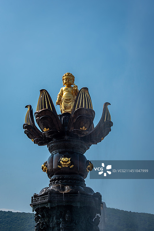 无锡灵山胜境九龙灌浴是国内最大的音乐动态青铜雕塑群，讲述释迦摩尼出生故事，蓝天下金色雕塑白色喷泉水柱图片素材