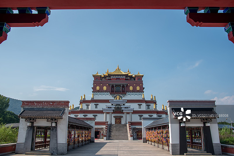 透过红色门框，看见蓝天白云下无锡灵山胜境的五印坛城西藏风格藏传佛教寺庙建筑图片素材