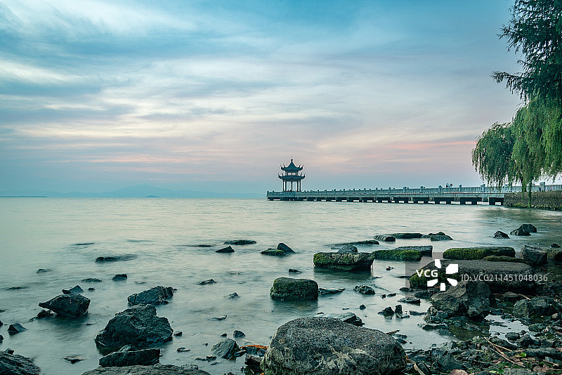 无锡拈花湾附近的太湖之滨十里明珠堤的日出朝霞红霞满天，中式凉亭和栈桥向太湖延伸，太湖水面平静如梦似幻图片素材