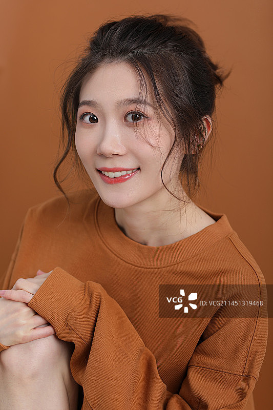 棕色背景下微笑的年轻女子的特写肖像图片素材